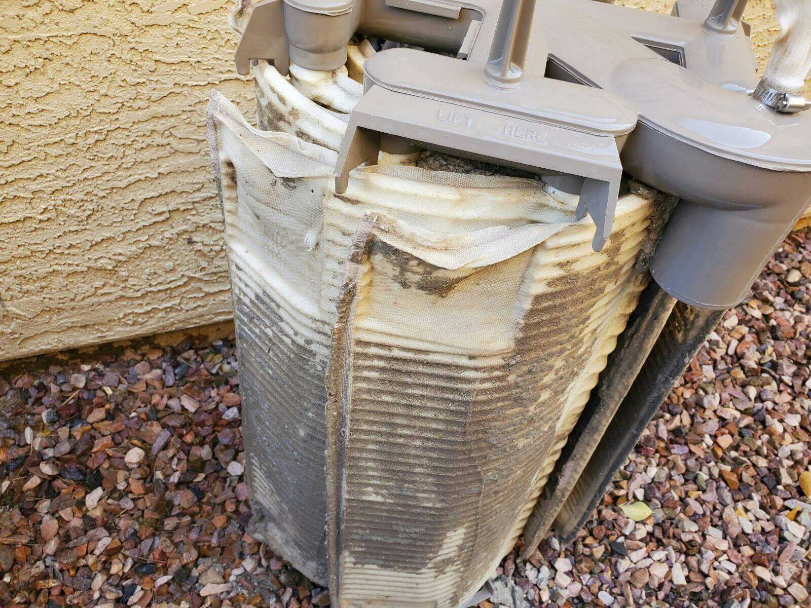 A clogged air conditioner in front of a house